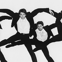 Thumbnail photo of Four men in suits dancin in air