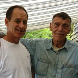 Thumbnail photo of two men posing one with arm around shoulder of the other