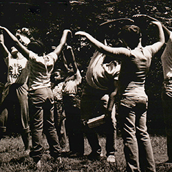 Thumbnail photo of Students and teacher in a circle with arms up