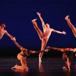 Thumbnail of Seven dancers on stage, four with their leg in the air, three on the ground
