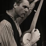 Thumbnail of man tuning banjo