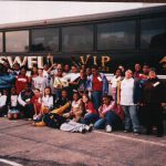 Thumbnail of group of students and teachers posing in front of a bus