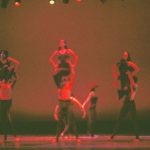 Thumbnail of Group of dancers lit in red, three being lifted