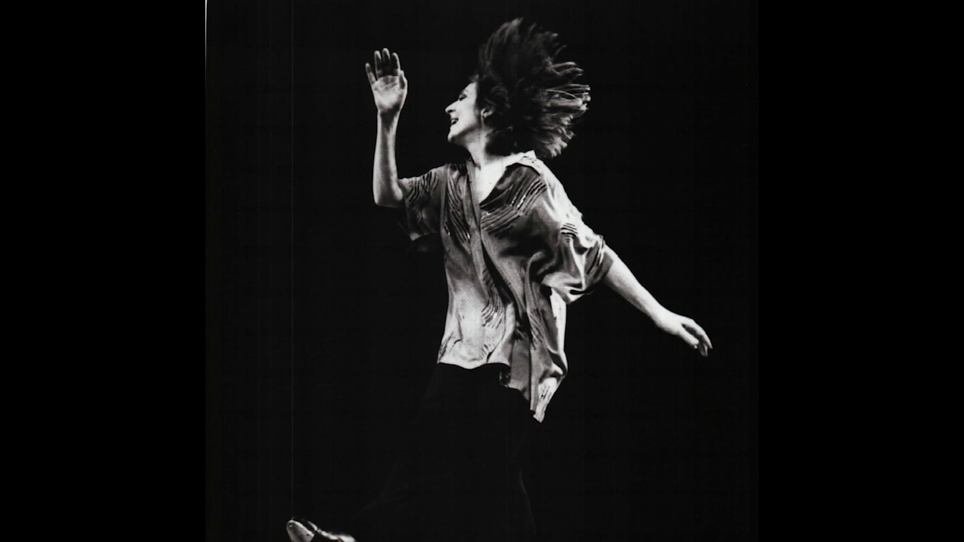 woman dancing one arm up in a wave the other behind her.